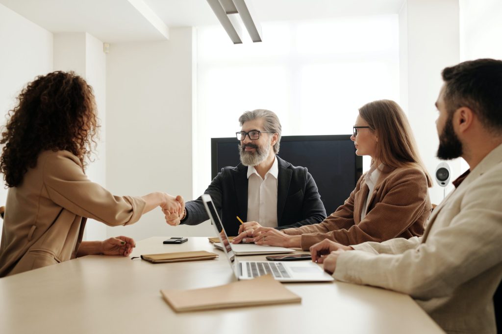 people around a table with man and woman shaking hands