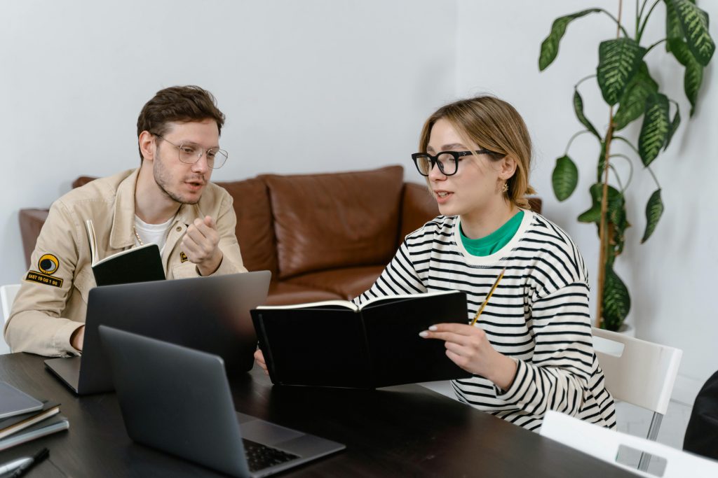 man and woman working at a table with computers and notebooks