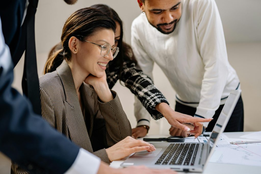 people gathered around a laptop pointing and smiling