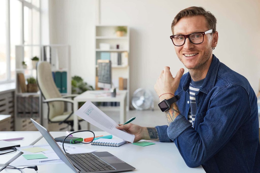 smiling man in glasses working at desk